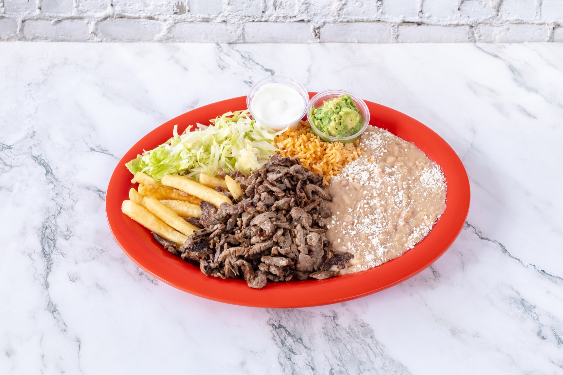 Asada fries plate with rice, beans, lettuce, guacamole, and sour cream