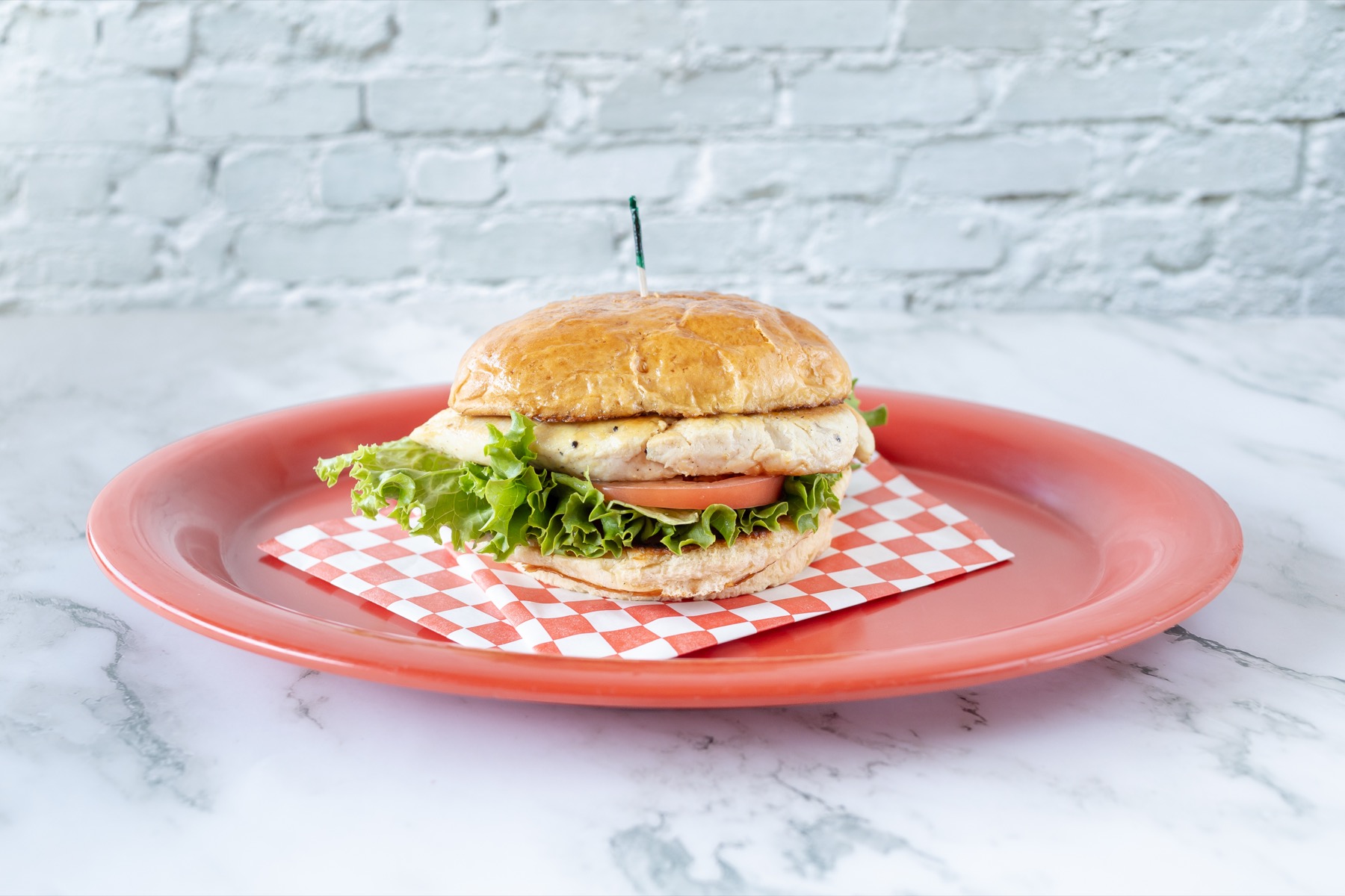 Chicken burger with lettuce and tomato on a red plate