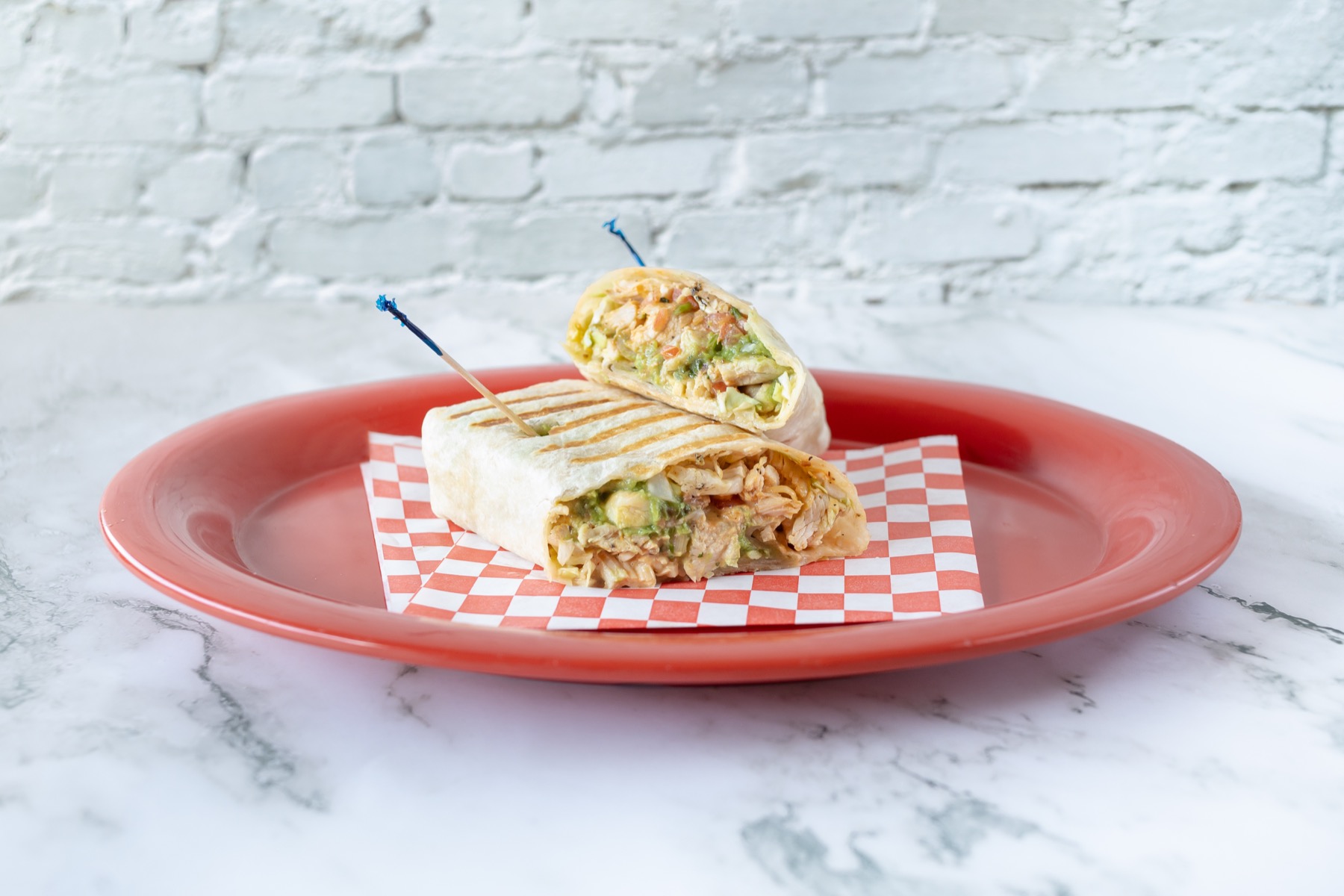 Grilled chicken wrap cut in half on a red plate