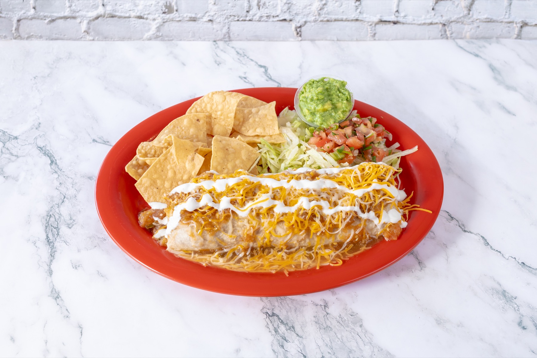 Wet burrito plate with tortilla chips, salad, pico de gallo, and guacamole